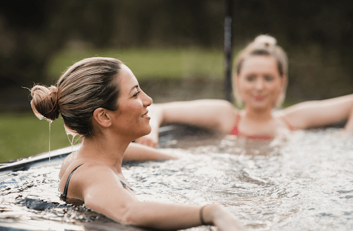 Two women relaxing in an outdoor spa in Balwyn, enjoying the serene surroundings.