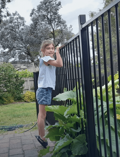 Child climbing a pool fence, highlighting safety risks associated with unmaintained pool barriers