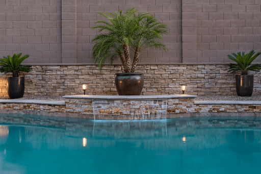 Modern backyard with landscaped pool area, feature wall, and potted palms—potential pool fence compliance considerations in Victoria