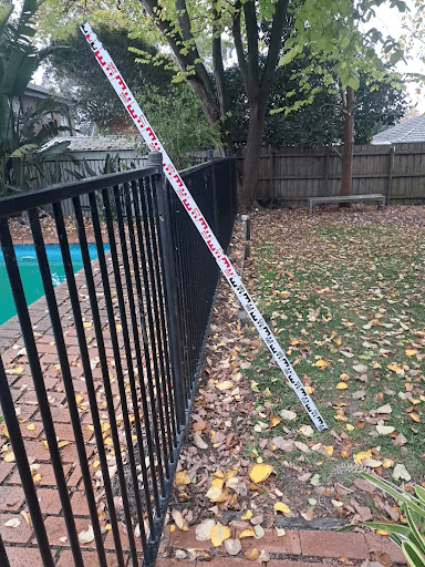 Pool fence in Victoria marked with a measuring pole during a compliance inspection, showing fence height assessment process